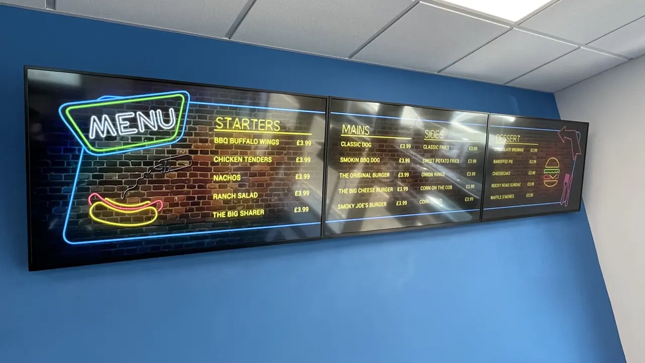 Digital menu board with a neon MENU header on a blue wall