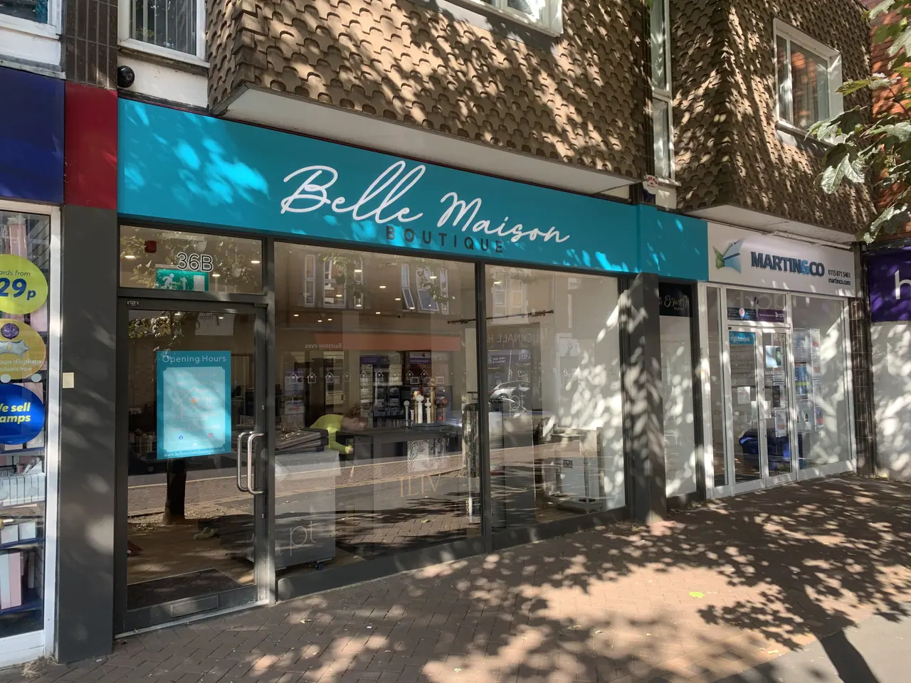 Teal fascia sign with script lettering on a shop front