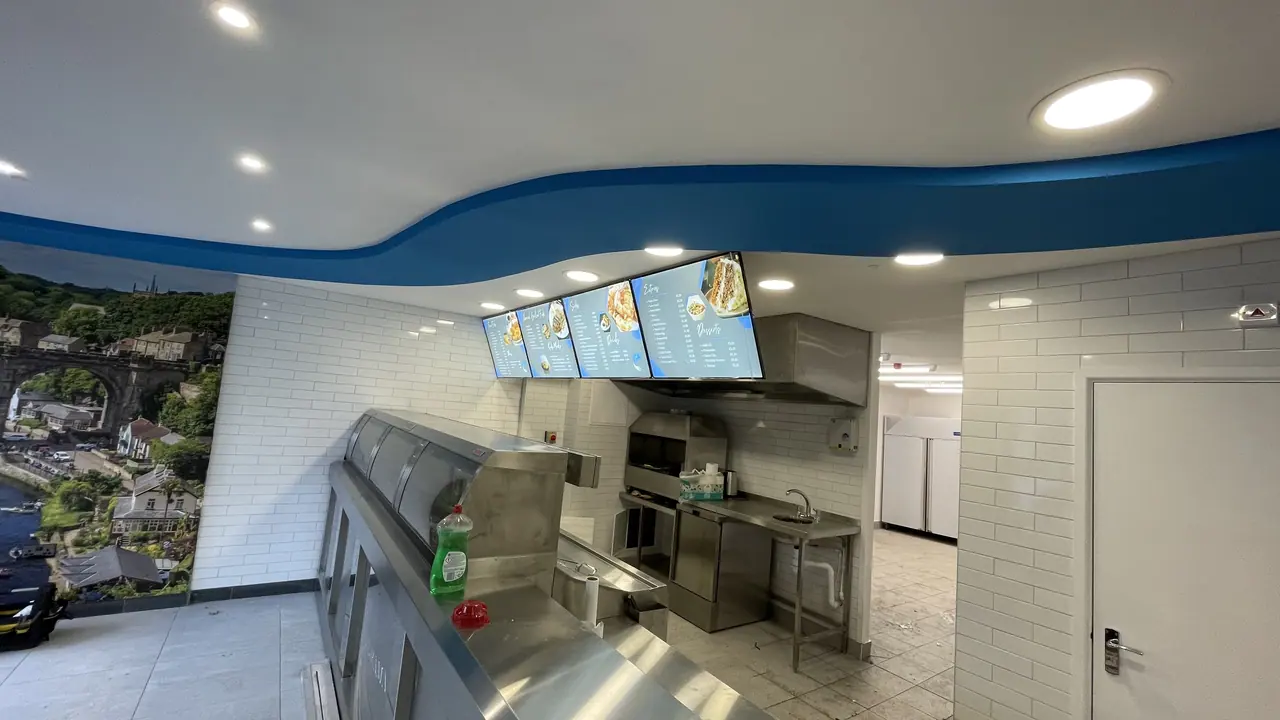Fish and chip shop counter with digital menu screens above